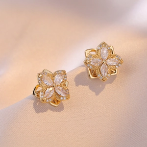 Golden flower earrings set with clear zircon on luxury champagne silk fabric backdrop