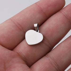 Close-up of polished silver heart pendant held in hand showing smooth mirror finish