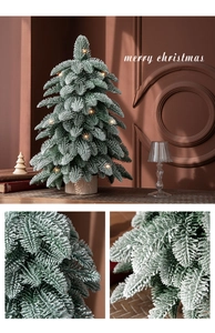 Close-up of snow-flocked green mini Christmas tree needles with warm LED lights and base