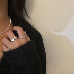 Close-up of minimalist S925 sterling silver knotted and twisted rings worn on fingers