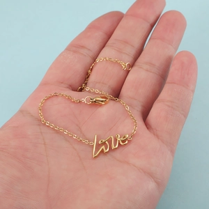 Bracelet élégant en acier inoxydable doré avec breloque love sur fond bleu clair