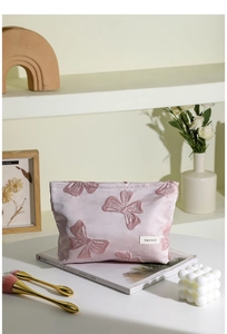 Beauty case rosa con fiocco 3D su scrivania con pennelli e decorazioni in dettaglio