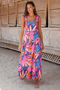 Detail of vibrant bohemian maxi dress with multi-tier floral print skirt on sunny beach