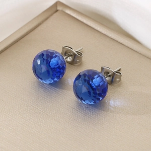 Macro view of blue faceted crystal stud earrings on a luxury golden display tray