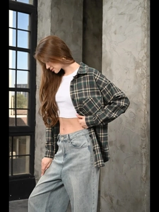 Detail of dark green plaid shirt paired with white crop top and light blue wide-leg jeans