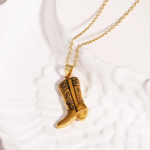 Goldene Titanstahl-Halskette mit Cowboy-Stiefel-Anhänger auf einer weißen Platte