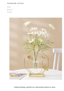 Detail view of a gold geometric metal vase with glass tube and ginkgo leaf bird accents