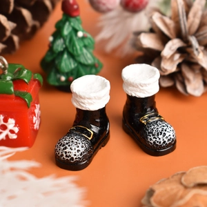 Macro shot of miniature black Christmas boots with white fur trim and silver patterns