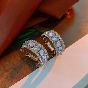 Gros plan de boucles d'oreilles créoles argentées avec zircons carrés et petits diamants