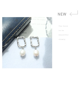 Detailed shot of irregular silver geometric metal frames with white pearl drop earrings