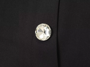 Detailed macro view of a large multifaceted crystal button on black fabric texture