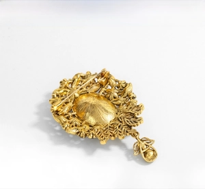 Macro view of the gold vintage brooch back showing radiant relief texture and safety pin clasp