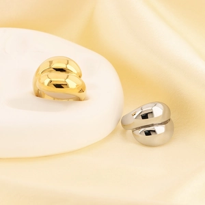 Polished gold and silver teardrop rings displayed on elegant silk fabric background