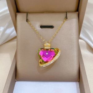 Close-up of heart-shaped crystal pendant with gold crown and sparkling zircon ring