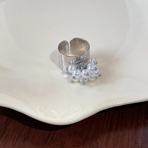 Detailed view of adjustable wide silver ring with delicate white pearl tassel on ceramic plate