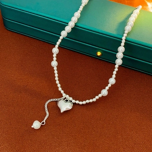 Elegant pearl choker necklace with silver heart pendant on a premium jewelry box