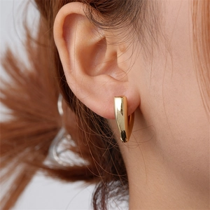 Close-up view of a model wearing minimalist golden V-shaped polished geometric earrings