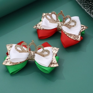 Detailed view of handmade Christmas hair bow clips with gold glitter crown and ribbon texture