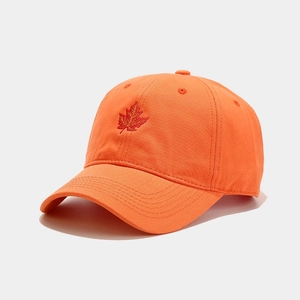 Detailed view of bright orange baseball cap featuring red maple leaf embroidery and soft fabric