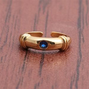 Detail of gold geometric ring featuring a central round blue zircon and retro engraving