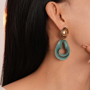 Detail view of vintage water drop earrings with teal resin and gold splash pattern