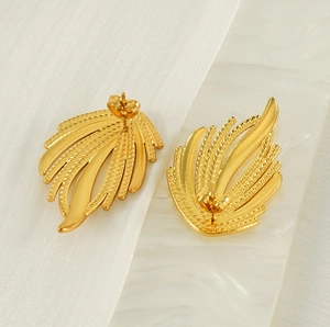 Vue détaillée de boucles d'oreilles ailes dorées avec motifs de plumes texturés fins