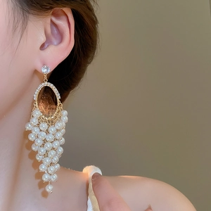 Close-up of elegant gold grape cluster drop earrings with white pearls on a model