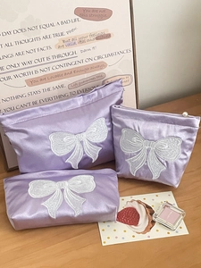 Elegant purple satin makeup bag with large white bow embroidery and pearl zipper detail