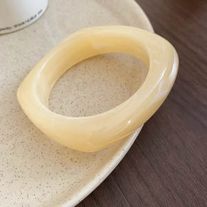 Detail of chunky beige acrylic bangle with marble pattern on ceramic display plate