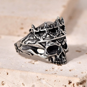 Gothic punk style stainless steel skull ring with crown on a natural stone surface
