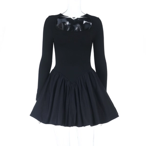 Détail d'une robe noire à manches longues avec encolure carrée et jupe plissée évasée