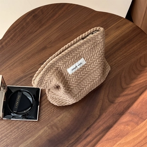 Detail of khaki knit makeup bag with textured wheat pattern and simple wish label