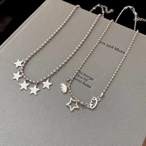 Detail of silver beaded necklaces with star pendants and purple zircon on book