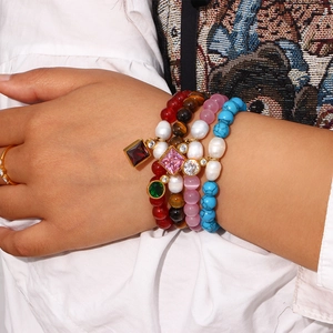 Close-up of stacked beaded bracelets with natural stones, freshwater pearls and zircon charms