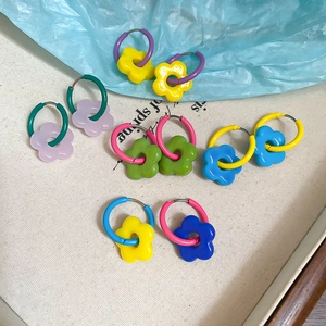 Flat lay of colorful acrylic flower hoop earrings on a canvas background with spring decor