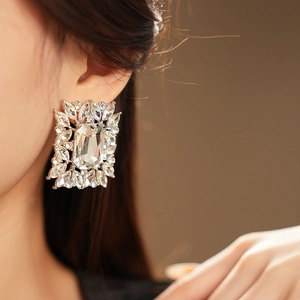 Close-up of silver square stud earring with crystal accents on a model's ear