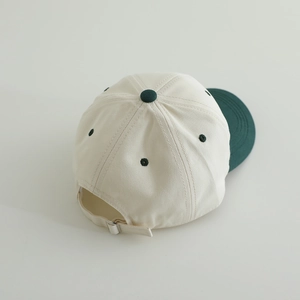 Top view of color-block cotton baseball cap with adjustable metal strap in cream and dark green