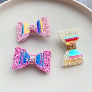 Detail of pink and yellow glitter bow hair clips with holographic center decoration