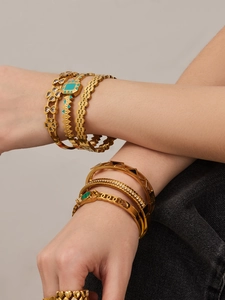 Detail of 18k gold bracelets with malachite and shell insets on a female wrist
