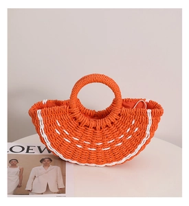Dettaglio di una borsa a mano intrecciata arancione con accenti bianchi e manico