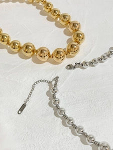Detail view of 18K gold and silver beaded necklaces showing S.STEEL material tag