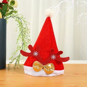 Red velvet Christmas hat with glitter antlers and gold bow on wooden tabletop