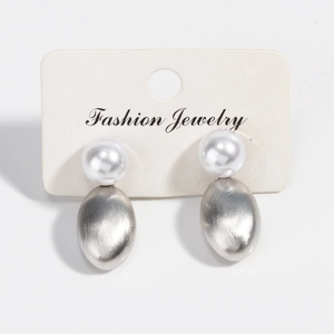 Detail of elegant pearl earrings with brushed silver metal on a fashion jewelry display card