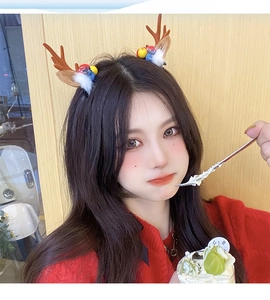 Close-up of a festive reindeer antler headband with colorful pom-poms and white feathers