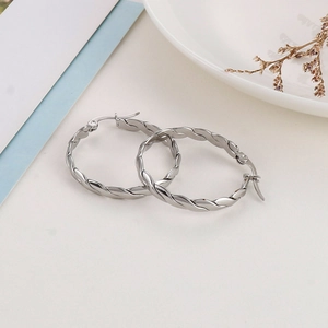 Detailed view of silver twisted rope hoop earrings on a decorative white porcelain plate