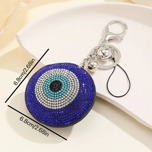 Macro shot of a blue rhinestone evil eye keychain with tassel on a ceramic plate