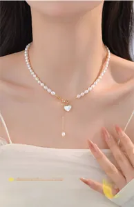 Close-up of natural freshwater pearl necklace with heart shell pendant and gold fringe