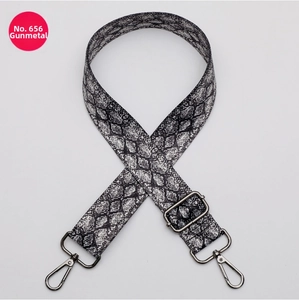 Detail of adjustable gunmetal lobster hooks and snake skin pattern on wide handbag strap
