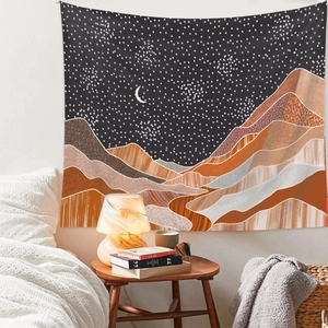 Cozy bedroom setting showing an abstract mountain and moon tapestry on the headboard wall