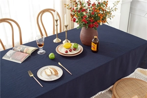 Close-up of a solid navy blue washed cotton tablecloth with white pompom tassel trim